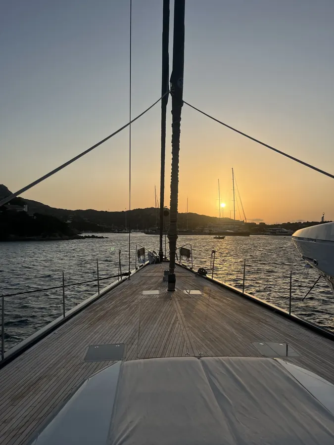 The foredeck of a sailing yacht at anchor at sunset